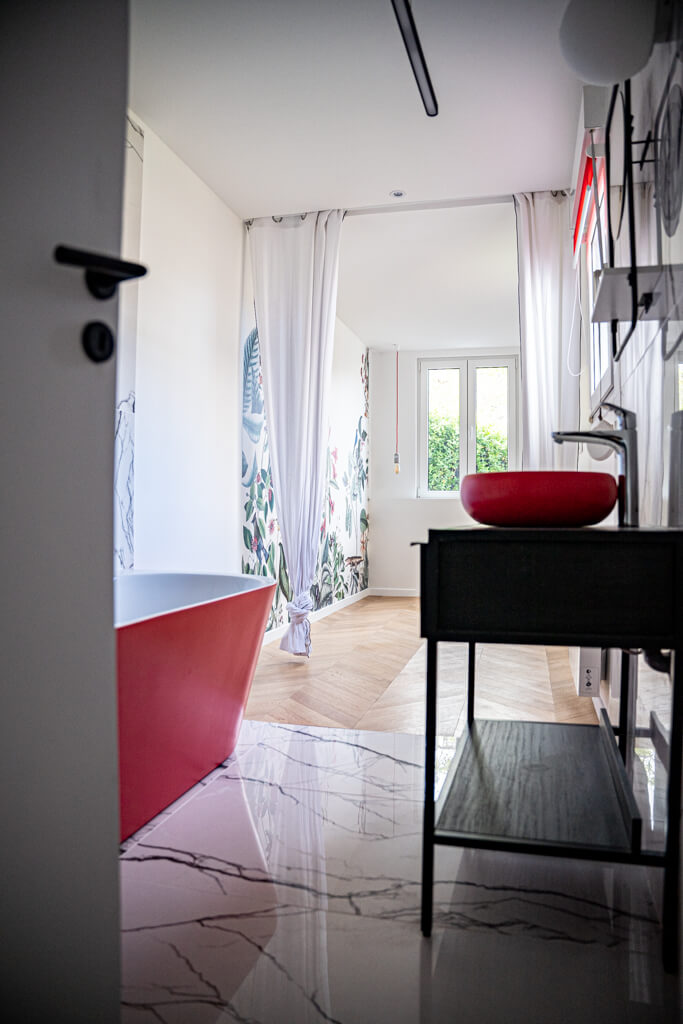 salle de bain en rez de chaussé avec baignoire rouge,lavabo rouge et marbre au sol